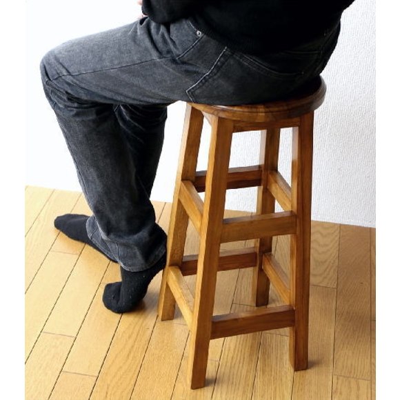 高さ60cmのチーク材スツールに座る男性